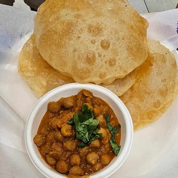 Golden-brown puri bread served with a bowl of chana masala, garnished with fresh cilantro.